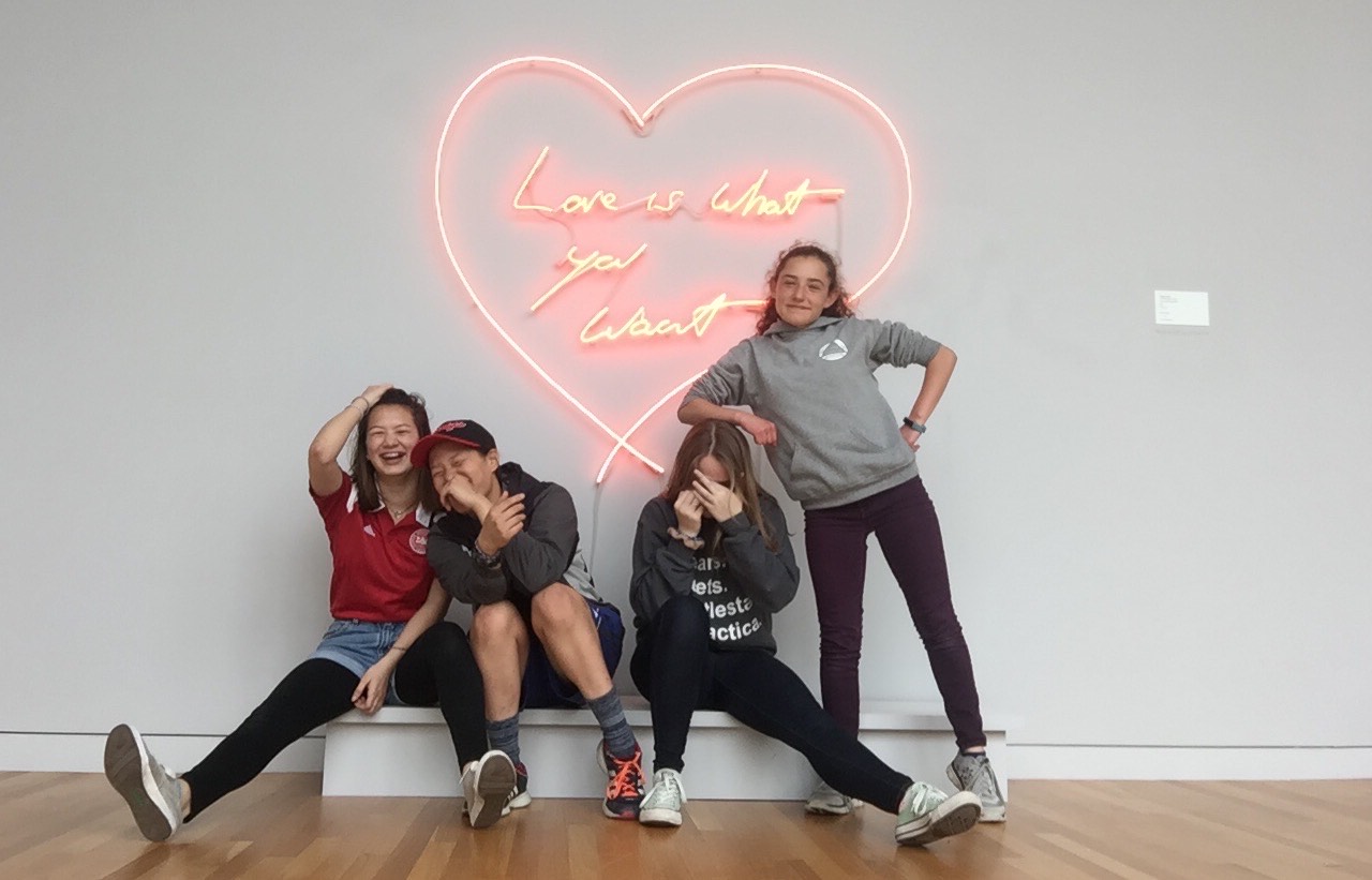 Rachel and three friends in front of a neon heart